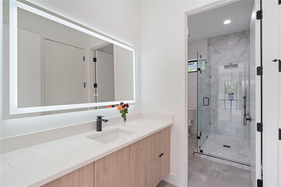 Full bathroom recessed lighting, front lit LED mirror, toilet, and vanity