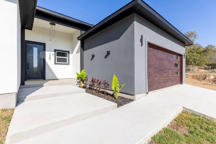 View of exterior entry featuring stucco siding, an attached garage, and driveway