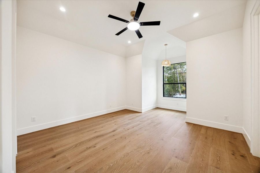 Fifth bedroom with white oak wood floors, recessed lighting, ceiling fan, and a window nook.