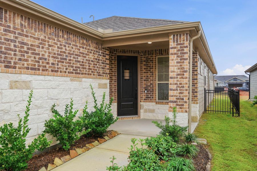 The covered porch and charming exterior create a welcoming entrance, with a landscaped walkway leading to a classic black front door that exudes warmth and curb appeal.