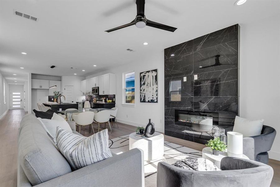 Living room with ceiling fan, a fireplace, and light hardwood / wood-style floors