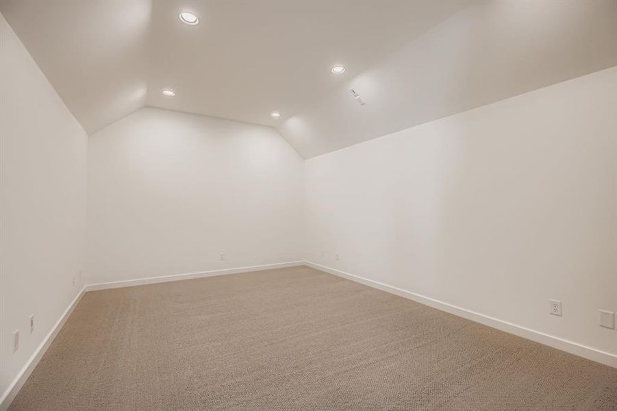 Empty room featuring lofted ceiling, light colored carpet, and recessed lighting Empty room featuring lofted ceiling, light colored carpet, and recessed lighting