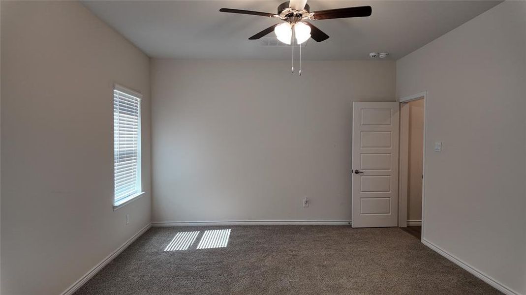 Carpeted empty room featuring a ceiling fan and baseboards