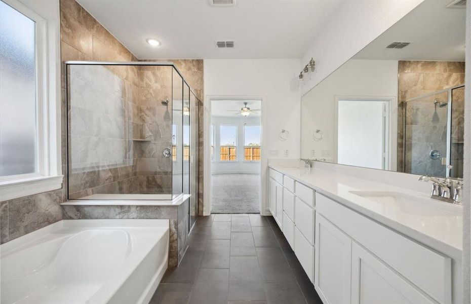 Elegant owner's bathroom with dual vanity and oversized shower *real home pictured