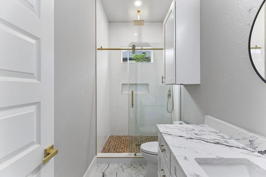 Marble vanity and sleek glass shower define this well-appointed bath.