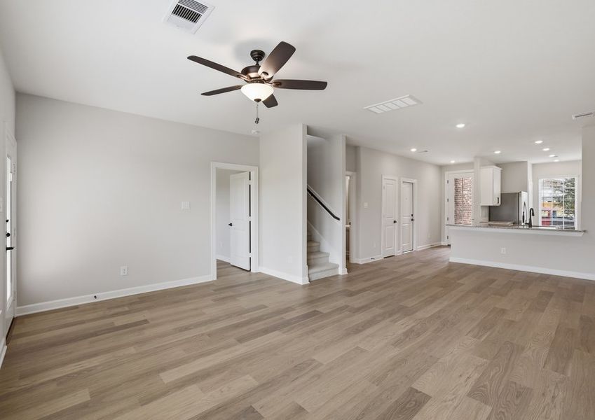 Living room featuring a ceiling fan, wood-look flooring, and an open-concept layout.