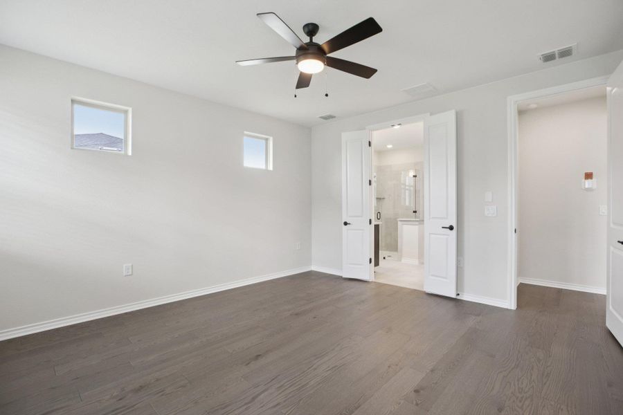 Unfurnished bedroom featuring dark wood-type flooring, a ceiling fan, and connected bathroom