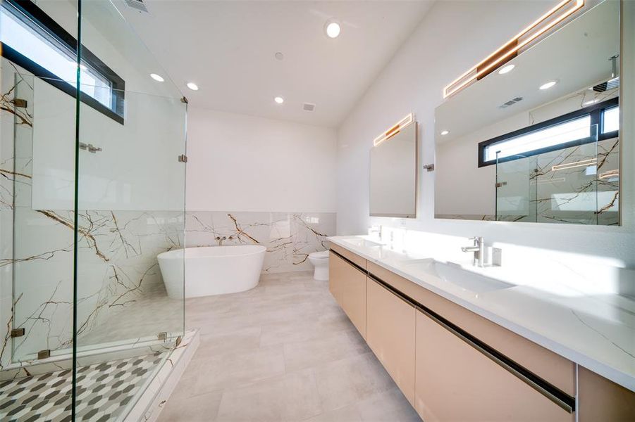 Full bathroom with vanity, toilet, tile walls, and separate shower and tub