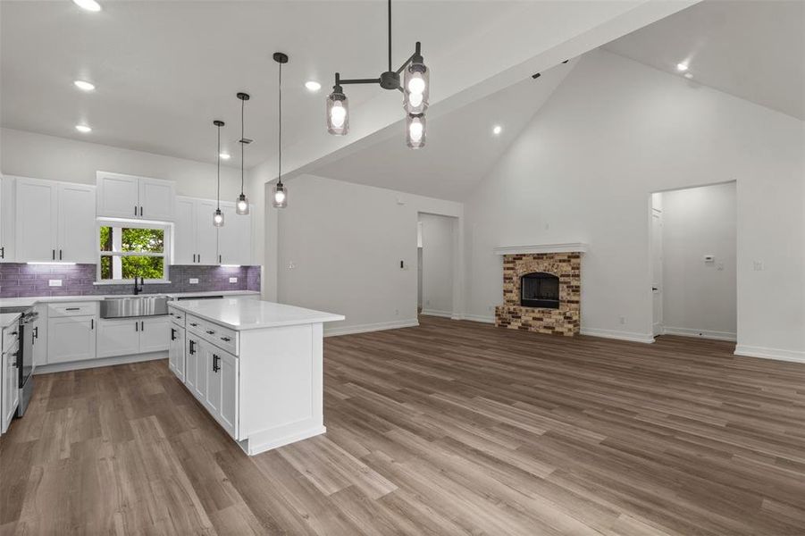 The property features an open-concept living space with vaulted ceilings, a brick and stone fireplace, and wood-look flooring