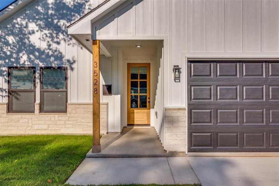 Doorway to property featuring board and batten siding and stone siding Doorway to property featuring board and batten siding and stone siding