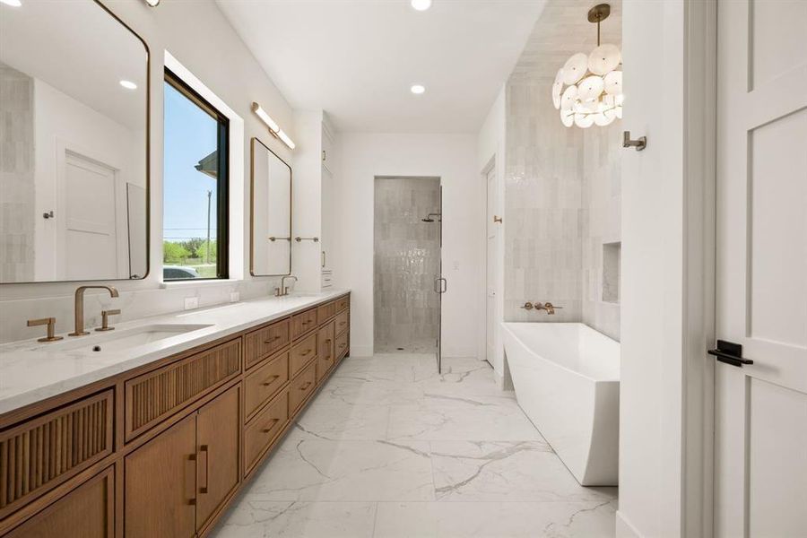 Resort Style Bathroom with a shower stall, a freestanding tub, marble finish flooring, double vanity, and recessed lighting