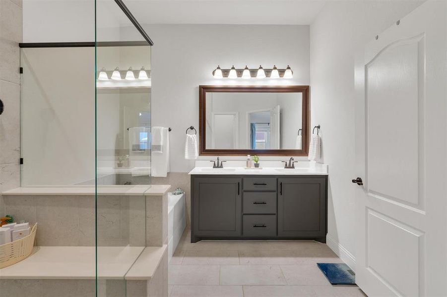 Bathroom featuring tile patterned flooring, vanity, and a shower