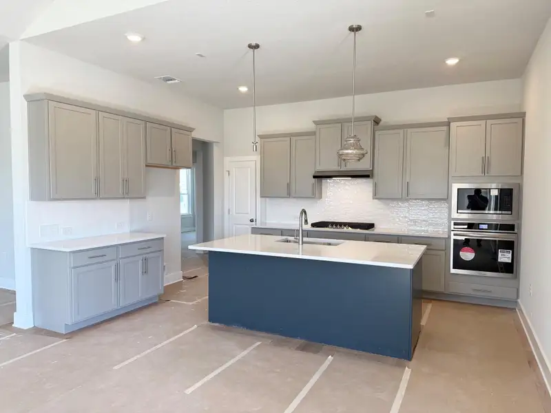 Kitchen featuring visible vents, gray cabinets, a sink, backsplash, and appliances with stainless steel finishes