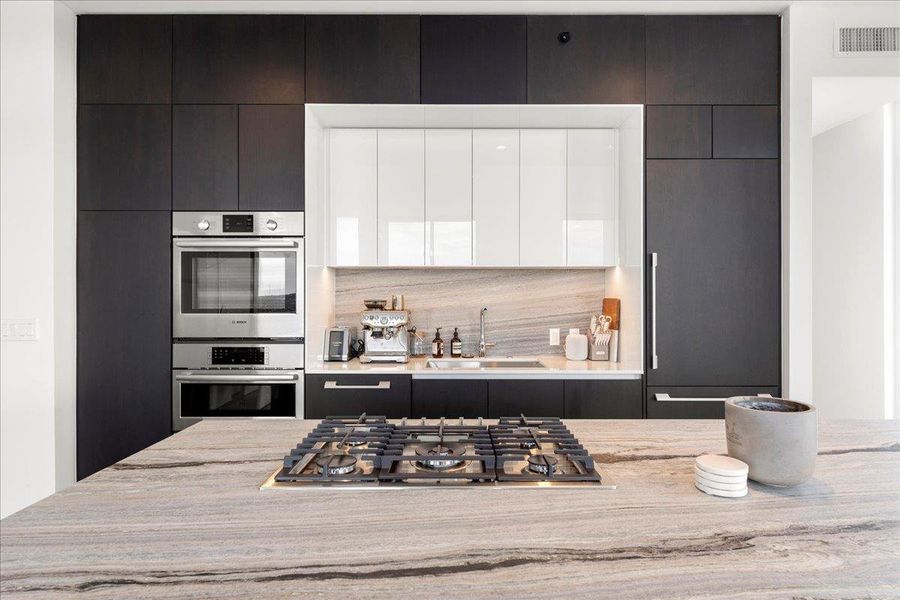 A modern chef’s kitchen anchored by upgraded Fantasy Ocean marble and equipped with Bosch appliances, integrated refrigeration and streamlined cabinetry.