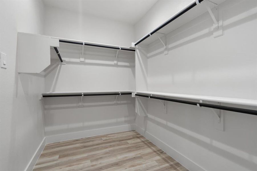 Spacious closet with light hardwood / wood-style flooring