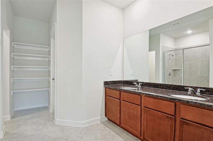 Bathroom with vanity, a shower with shower door, and tile patterned floors