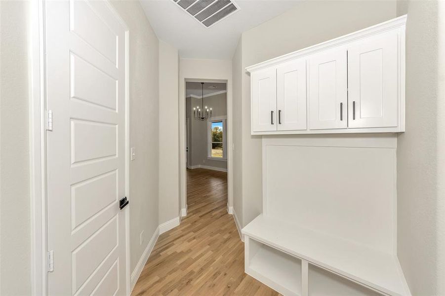 Mudroom with light hardwood / wood-style floors and a notable chandelier