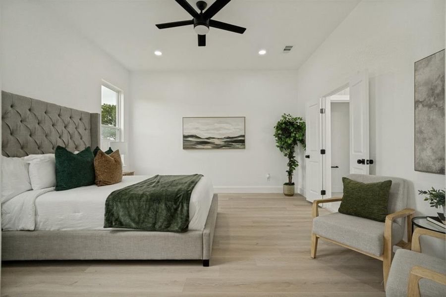 Spacious room featuring light wood-finish flooring, a contemporary black ceiling fan, recessed lighting, and white double doors with black hardware Spacious room featuring light wood-finish flooring, a contemporary black ceiling fan, recessed lighting, and white double doors with black hardware