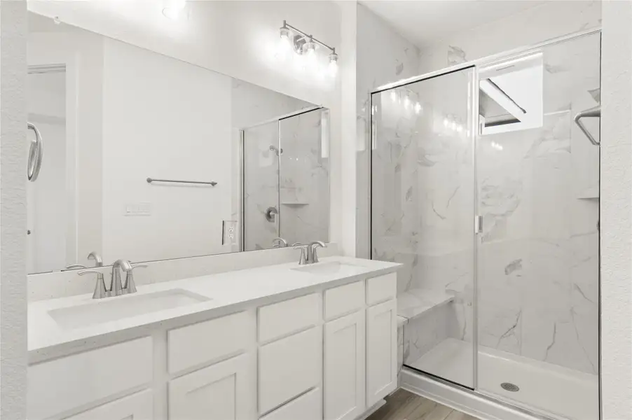 Full bathroom with a marble finish shower, double vanity, and wood finished floors