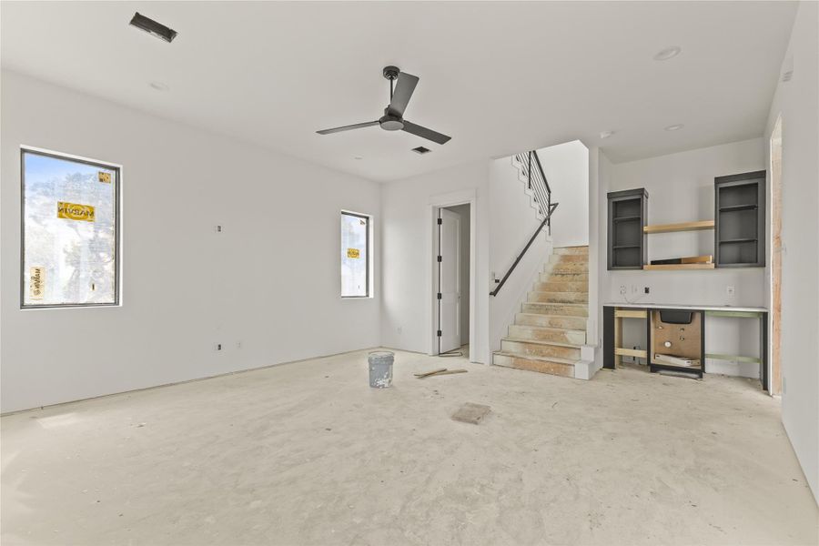 Open concept interior with large windows and a ceiling fan