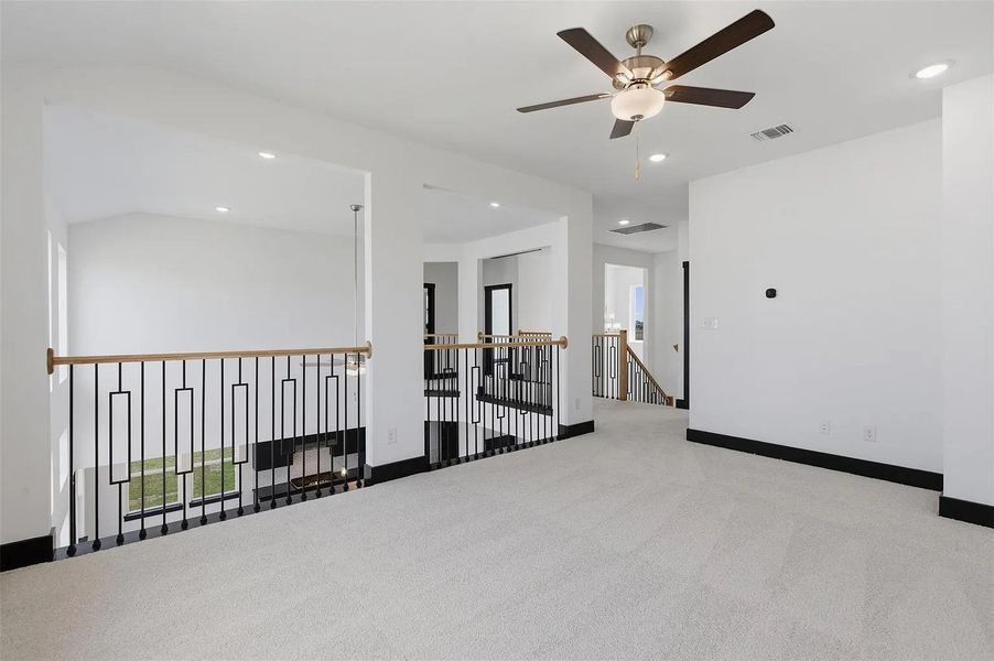 A versatile open-concept loft space features a decorative railing overlooking the lower level. A versatile open-concept loft space features a decorative railing overlooking the lower level.