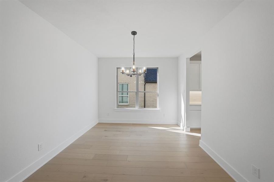 Unfurnished dining area featuring a chandelier and light wood-style flooring Unfurnished dining area featuring a chandelier and light wood-style flooring