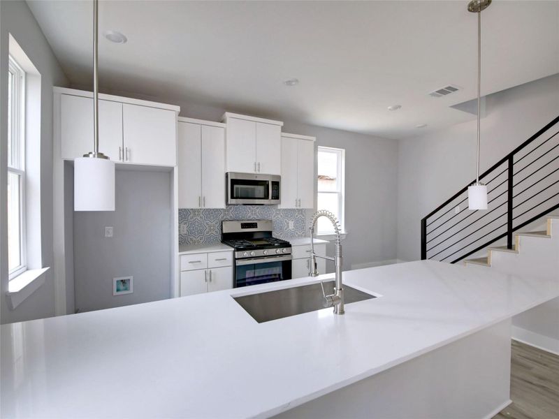 Kitchen featuring pendant lighting, appliances with stainless steel finishes, and white cabinetry
