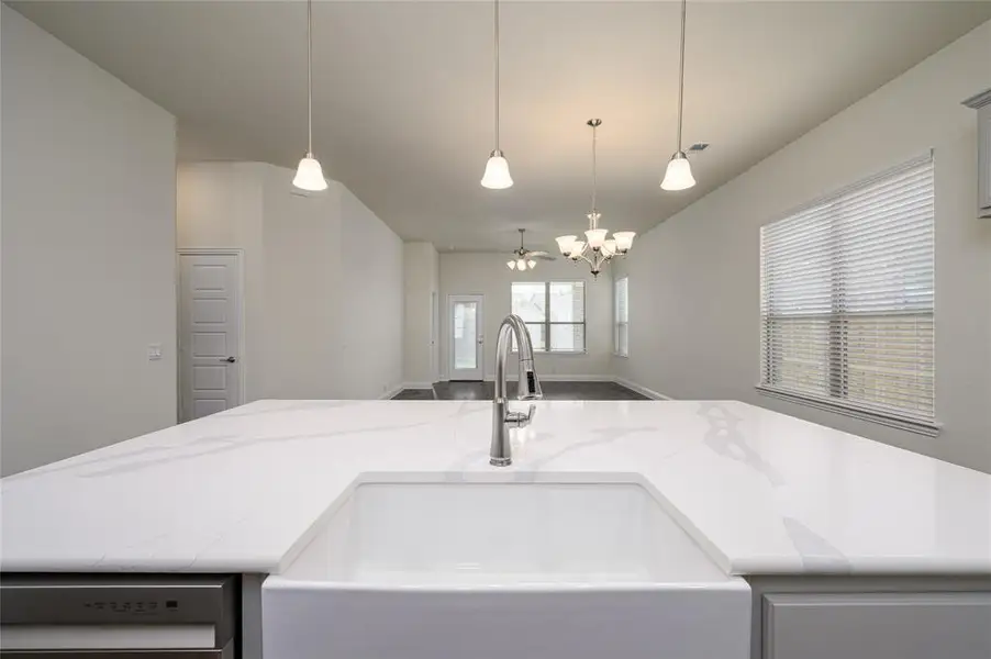 Kitchen with farm house sink, decorative light fixtures, and an island with sink