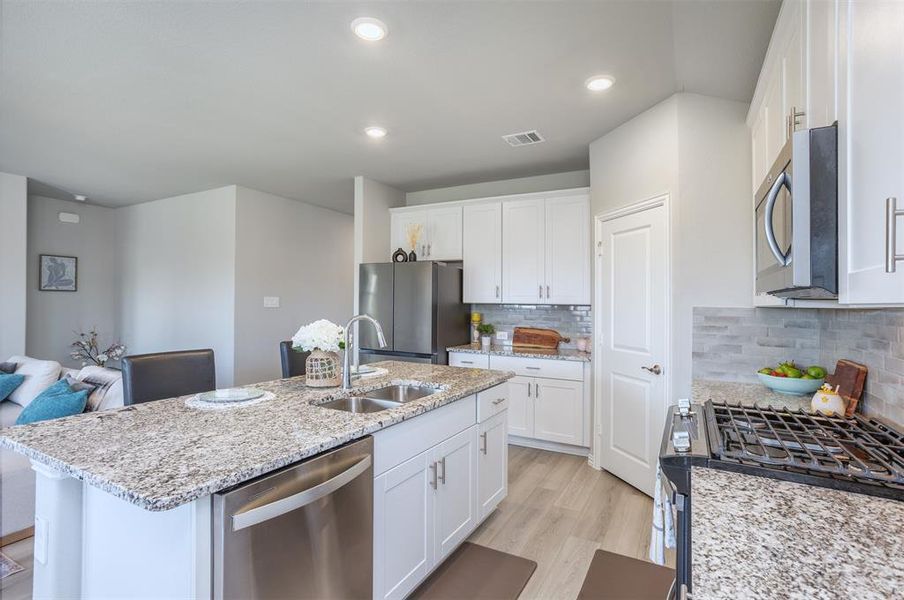 Kitchen featuring stainless steel appliances, white cabinetry, light stone countertops, backsplash, and recessed lighting Kitchen featuring stainless steel appliances, white cabinetry, light stone countertops, backsplash, and recessed lighting