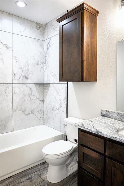 Secondary bathroom featuring vanity, tiled shower / bath, and toilet