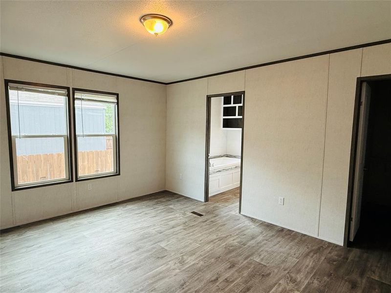 Empty room featuring wood finished floors, a textured ceiling, and a decorative wall