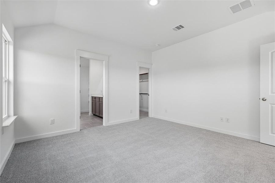 Unfurnished bedroom featuring a walk in closet, light colored carpet, vaulted ceiling, and ensuite bathroom Unfurnished bedroom featuring a walk in closet, light colored carpet, vaulted ceiling, and ensuite bathroom