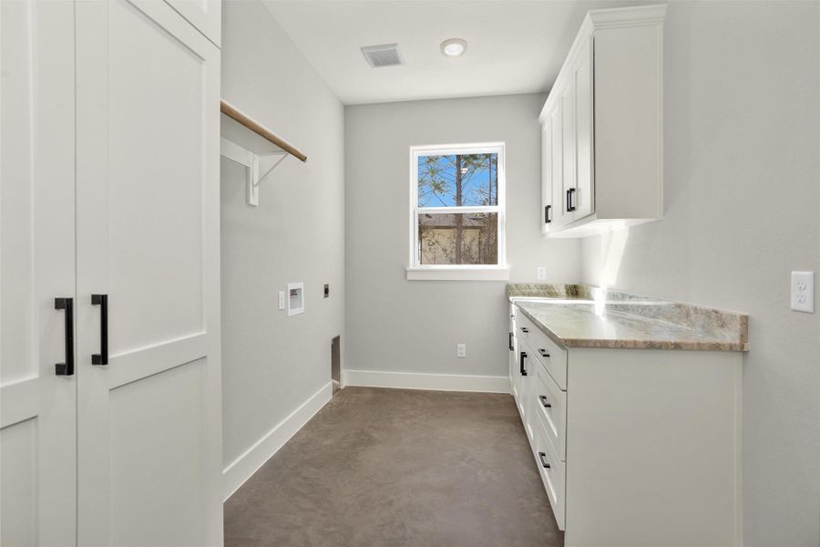The oversized utility room offers exceptional space and functionality, complete with additional closets, ample cabinetry, and generous countertop space for folding and organizing. Designed with storage in mind, this well-appointed area keeps household essentials neatly tucked away while providing room to move comfortably.