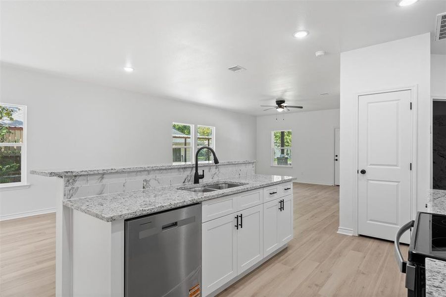 Kitchen featuring light stone countertops, light wood finished floors, dishwasher, white cabinets, and black electric range oven