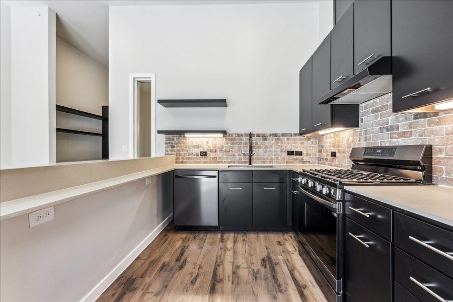 A well-appointed kitchen features dark cabinetry, stainless steel appliances, and wood flooring. A well-appointed kitchen features dark cabinetry, stainless steel appliances, and wood flooring.