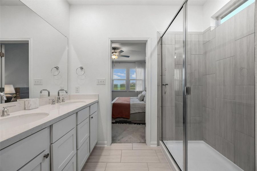 Contemporary bathroom featuring a double vanity with light-toned countertops, a full-width mirror, and two undermount sinks
