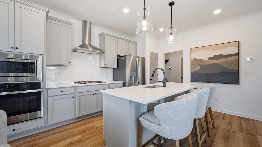 Modern kitchen with stacked microwave and oven, quartz countertops, and sleek cabinetry in townhome in Loganville, GA.