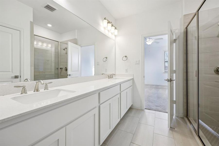 Primary Bathroom featuring ceiling fan, tile patterned floors, walk in shower, and vanity