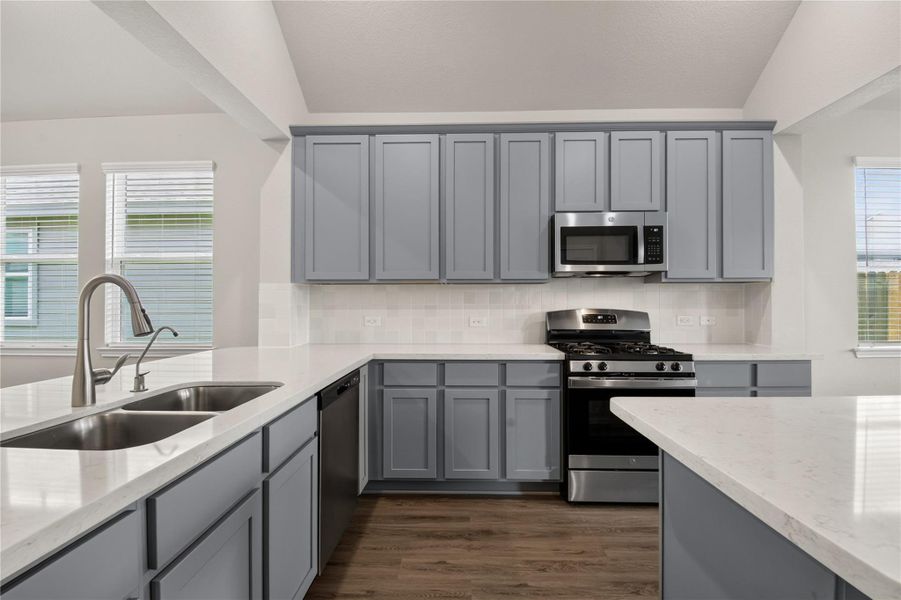 This modern kitchen features sleek gray cabinetry, a spacious white countertop with a double sink. The open layout provides ample natural light and flows seamlessly into the adjoining living area, perfect for entertaining. This modern kitchen features sleek gray cabinetry, a spacious white countertop with a double sink. The open layout provides ample natural light and flows seamlessly into the adjoining living area, perfect for entertaining.