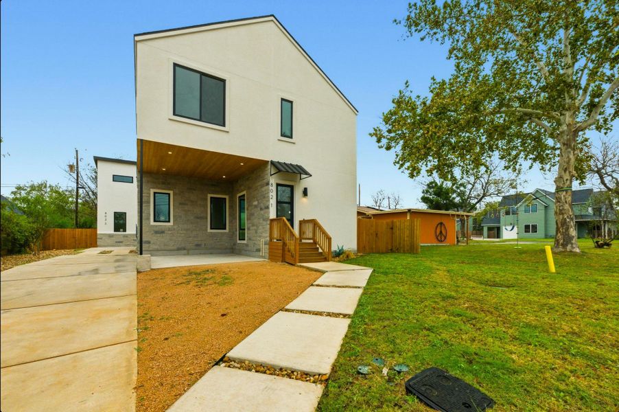View of front of property featuring stone siding, a patio area, and stucco siding