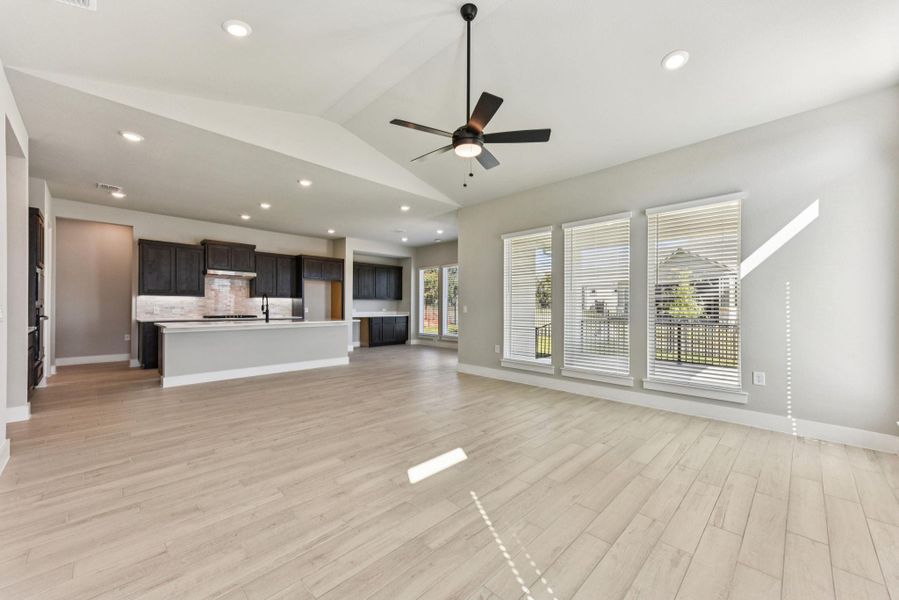 Unfurnished living room featuring lofted ceiling, light wood-type flooring, a ceiling fan, and recessed lighting