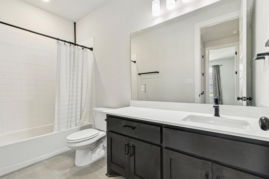 Bathroom with shower / tub combo, vanity, and light tile patterned floors Bathroom with shower / tub combo, vanity, and light tile patterned floors