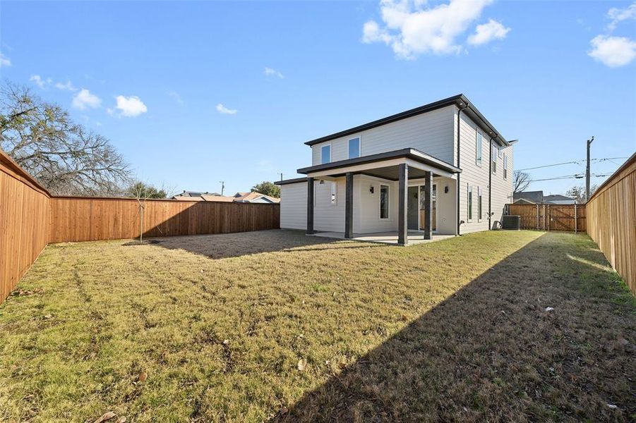 Back of property with central AC, a lawn, and a patio