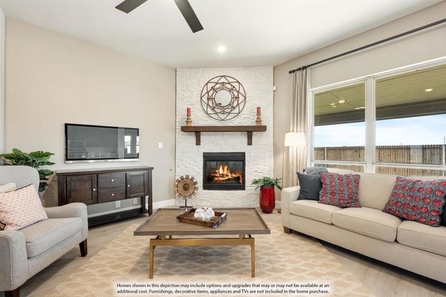 Living room with white stone corner fireplace, ceiling fan, sofa, and large windows Living room with white stone corner fireplace, ceiling fan, sofa, and large windows
