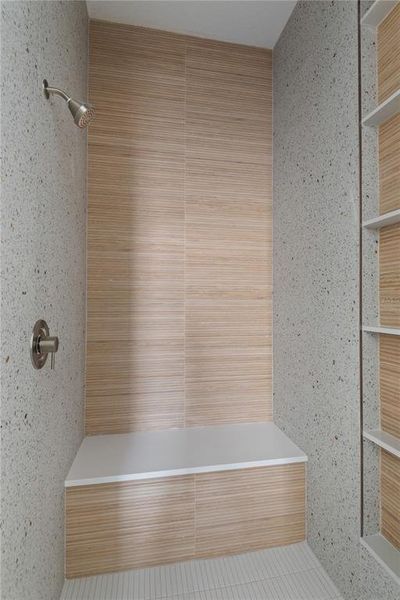 Spa-like shower experience with a large walk-in shower featuring a rain showerhead, a built-in bench seat, and a sleek wood-look tile accent wall.