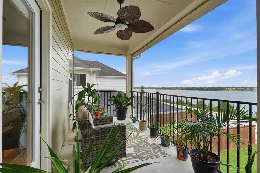 Covered balcony with a ceiling fan, offering broad water views and a black wrought iron railing Covered balcony with a ceiling fan, offering broad water views and a black wrought iron railing