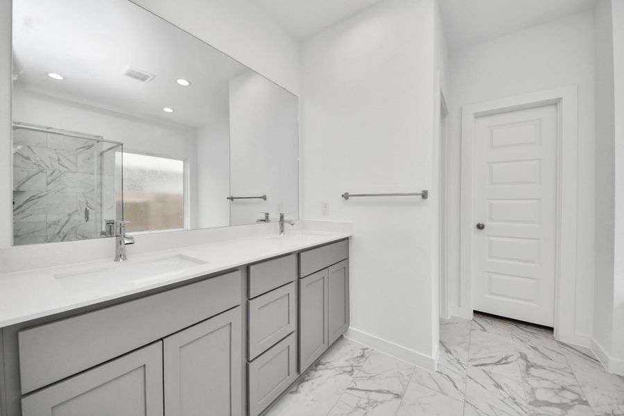 Indulge in a spa-like retreat within the confines of this primary bathroom. Delight in a spacious walk-in shower enveloped in stylish tile surround, unwind in a separate garden tub adorned with custom detailing. Sample photo of completed home with similar floor plan. Actual colors and selections may vary.