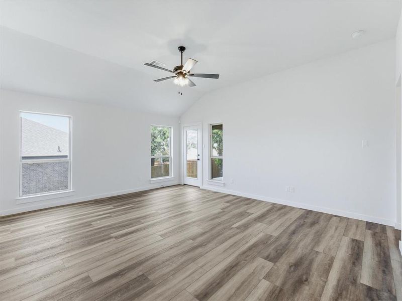 Spacious interior with vaulted ceilings, wood-finish flooring, white walls, and a ceiling fan Spacious interior with vaulted ceilings, wood-finish flooring, white walls, and a ceiling fan
