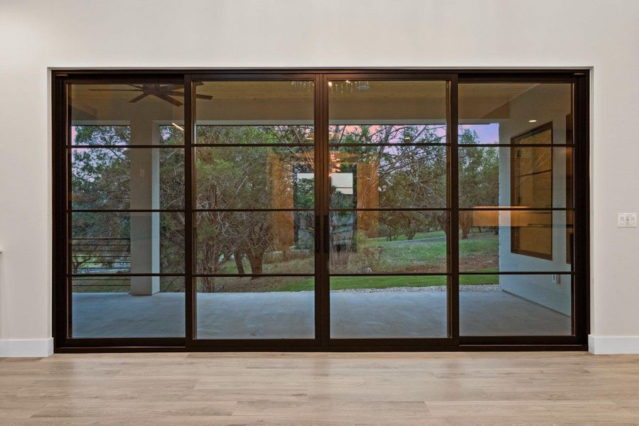 Floor-to-ceiling glass sliding doors provide natural illumination and views of the surrounding natural landscape.