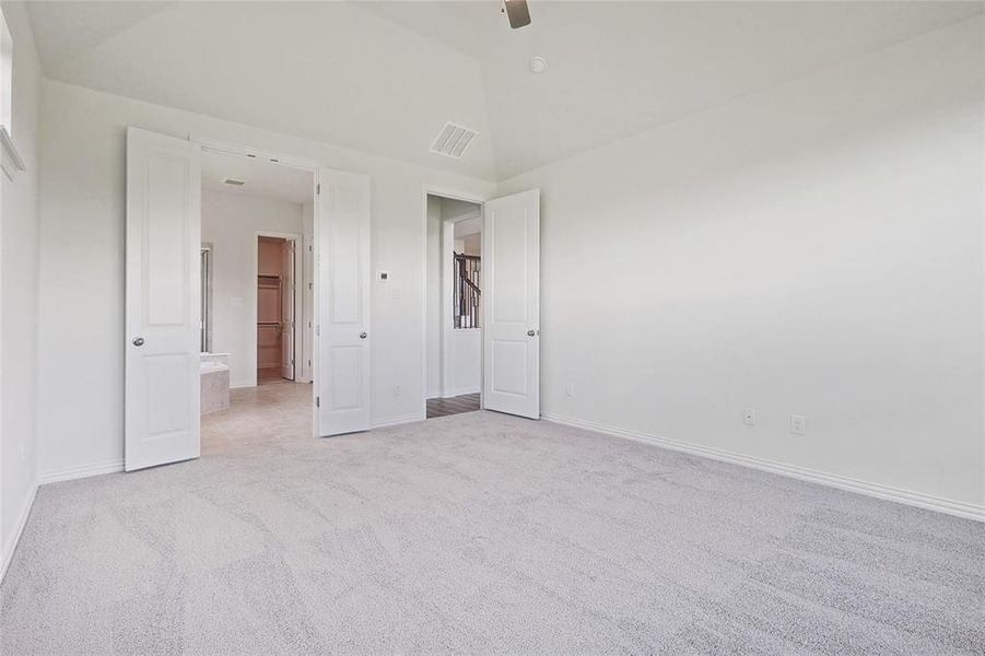 Unfurnished bedroom with ceiling fan, light colored carpet, and vaulted ceiling